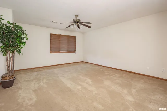 an empty room with potted plants and a chandelier fan