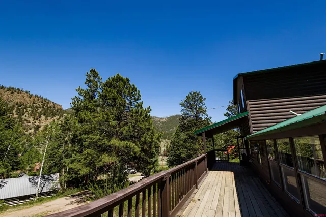 a balcony with wooden floor and trees in the background