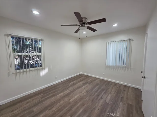 an empty room with wooden floor closet and windows