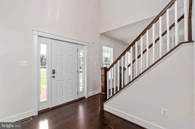 an empty room with wooden floor chandelier and windows