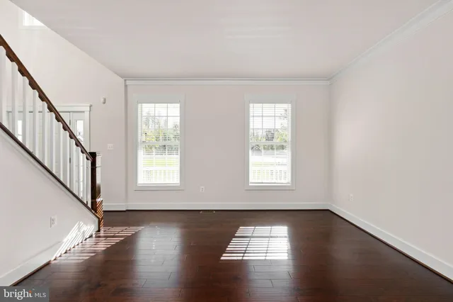 a view of an empty room with window and wooden floor
