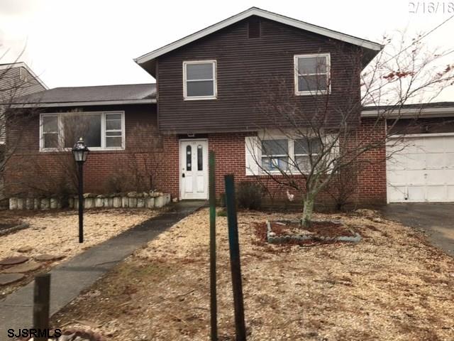 a brick house that has a tree in front of it