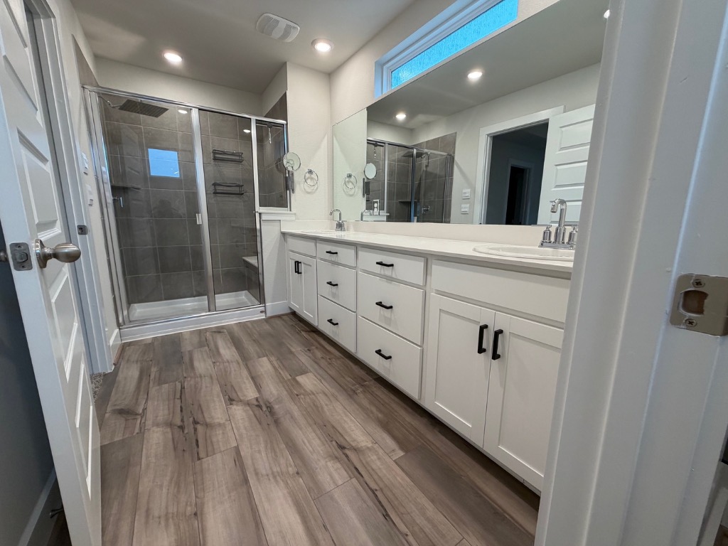 7417 Acela Trail, Unit 231 Austin, TX 78744 - Photo 12 of 15 Full bathroom featuring double vanity, dark wood-style flooring, a shower stall, and recessed lighting