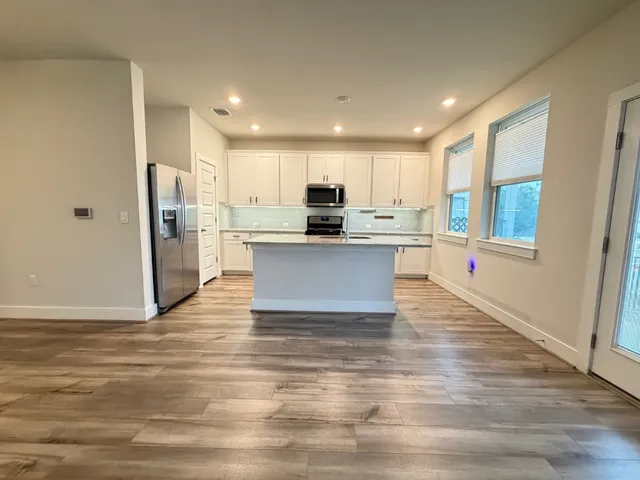 a view of kitchen with granite countertop refrigerator stove microwave and cabinets