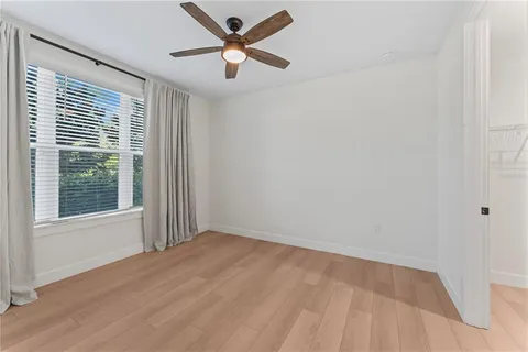 a view of empty room with wooden floor and ceiling fan