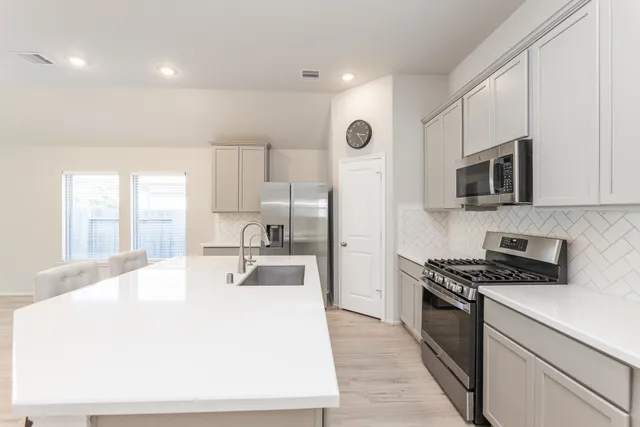 a kitchen with kitchen island a sink stainless steel appliances and cabinets