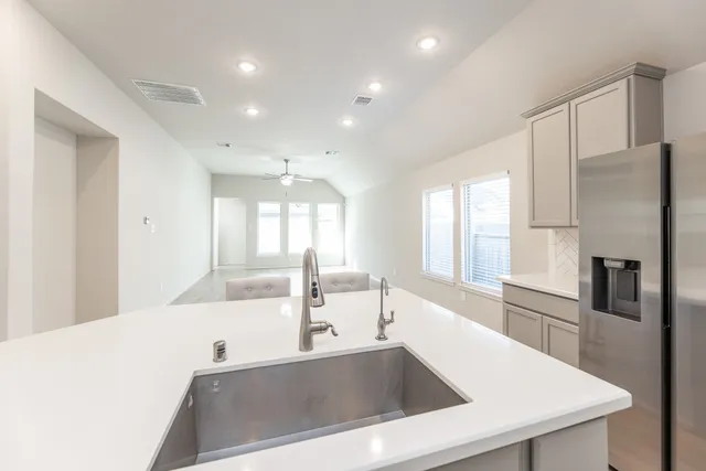 a large kitchen with stainless steel appliances a large counter top a refrigerator and a sink