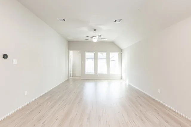 a view of an empty room with a window and wooden floor