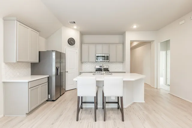 a kitchen with stainless steel appliances a dining table chairs and wooden floor