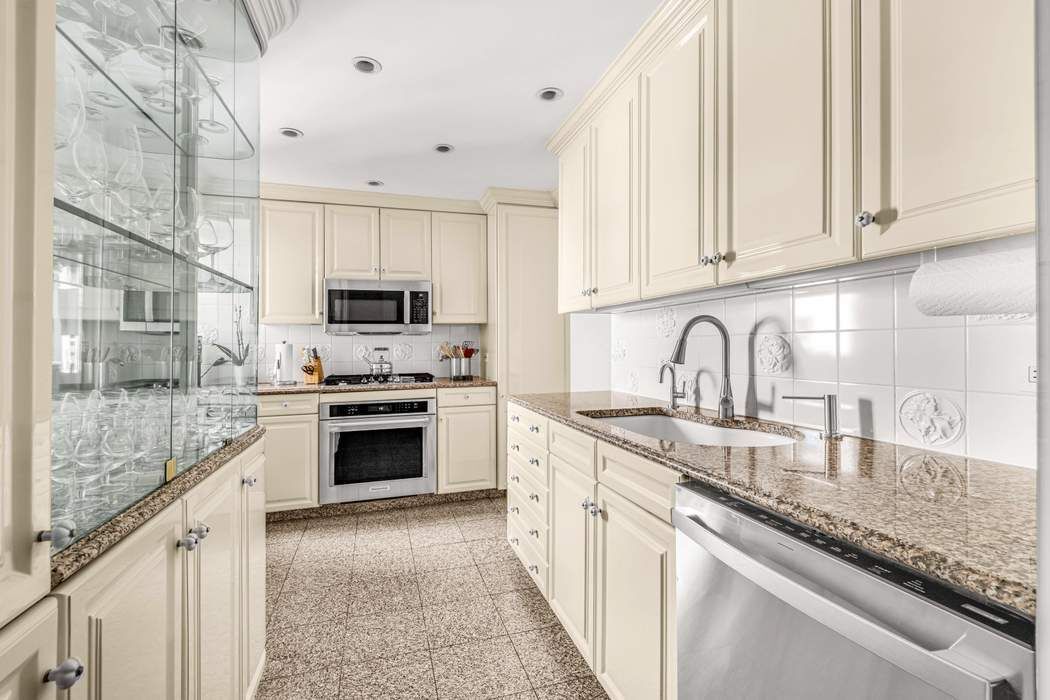 860 5th Avenue, Unit 9/10JK Manhattan, NY 10065 - Photo 7 of 19 a kitchen with granite countertop white cabinets and stainless steel appliances