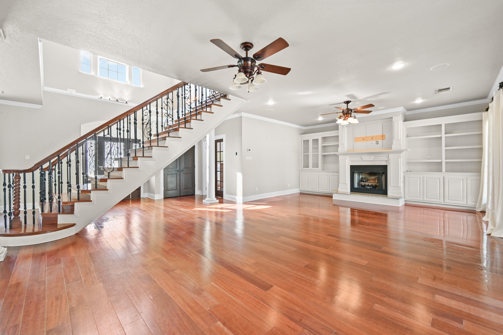 1175 Southern Way Luling, TX 78648 - Photo 18 of 40 Hardwood floors gleam across this living space, featuring a stately fireplace and a grand staircase.