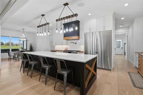 a kitchen with kitchen island a dining table chairs stainless steel appliances and cabinets
