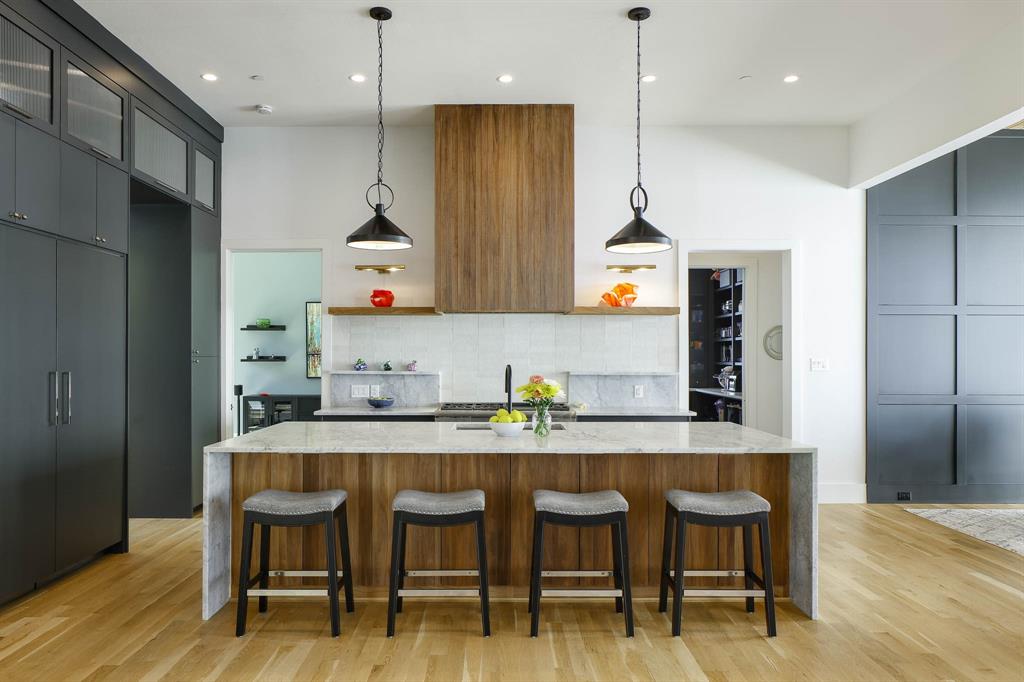 7149 Northaven Road Dallas, TX 75230 - Photo 2 of 25 a kitchen with kitchen island stainless steel appliances a dining table chairs sink and wooden floor