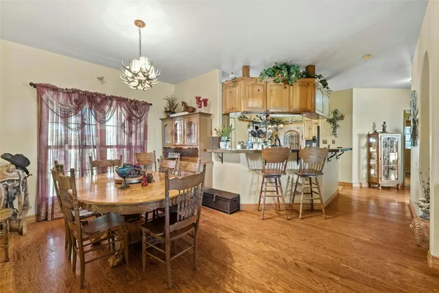 a view of a dining room and livingroom with furniture wooden floor a chandelier