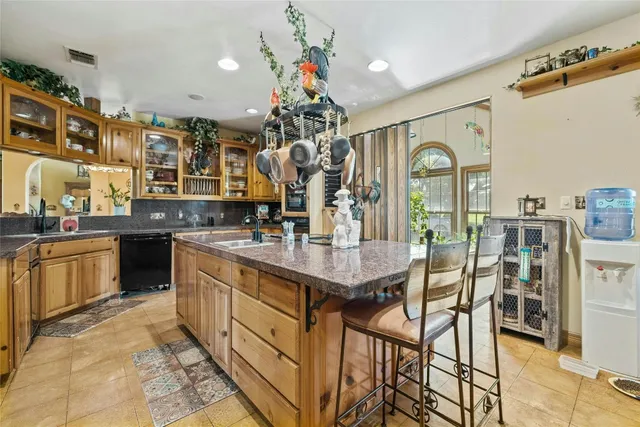 a kitchen with stainless steel appliances kitchen island granite countertop a table chairs in it and a a sink