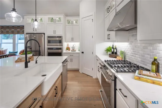 a kitchen with stainless steel appliances a stove a sink and white cabinets