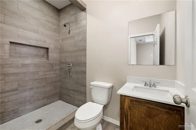 a bathroom with a granite countertop toilet a sink a mirror and shower