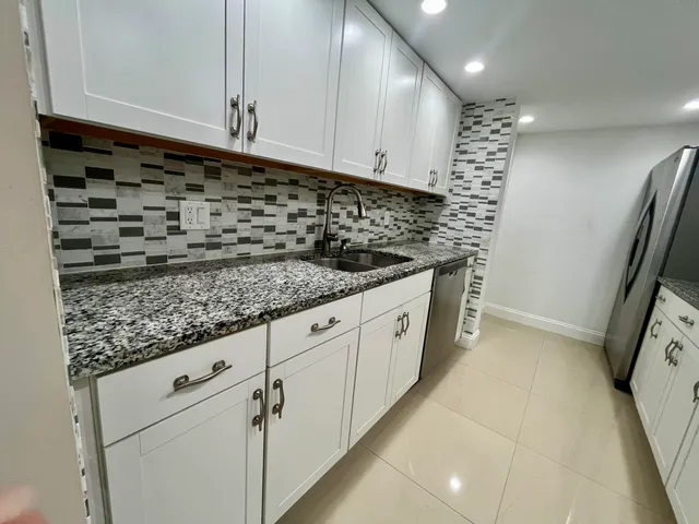 a kitchen with granite countertop white cabinets and white appliances