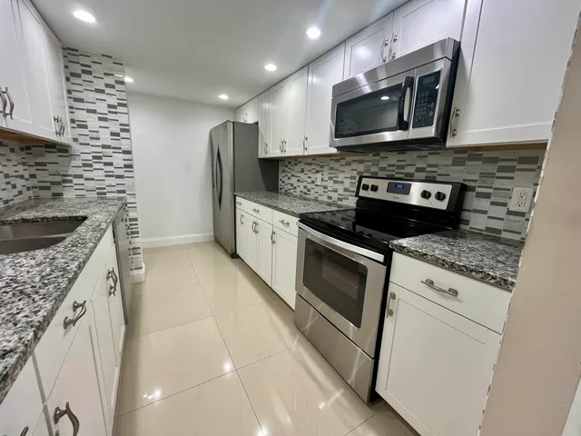 a kitchen with stainless steel appliances kitchen island granite countertop a stove microwave and sink