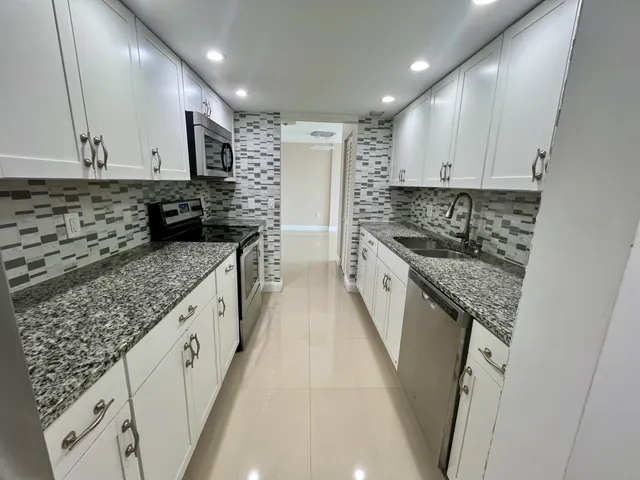 a kitchen with granite countertop a sink stove and cabinets