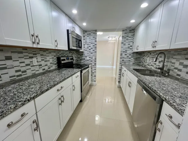 a kitchen with granite countertop a sink stove and cabinets