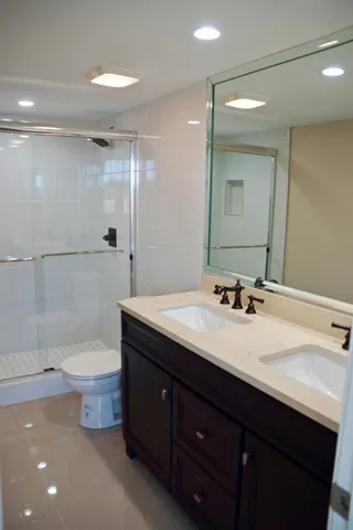 a bathroom with a double vanity sink toilet and shower