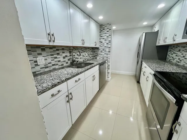 a kitchen with granite countertop a sink a stove and cabinets