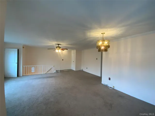 wooden floor in an empty room with a chandelier fan