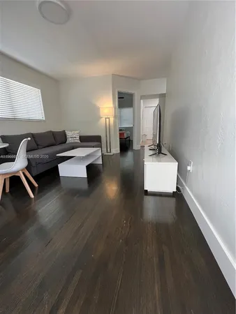a living room with couches and kitchen view with wooden floor