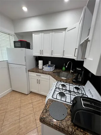 a kitchen with granite countertop a sink a stove and refrigerator