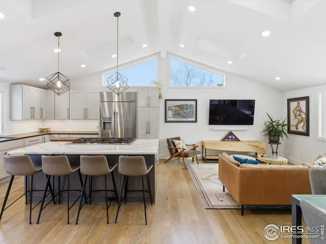 a living room with stainless steel appliances kitchen island granite countertop furniture and a flat screen tv