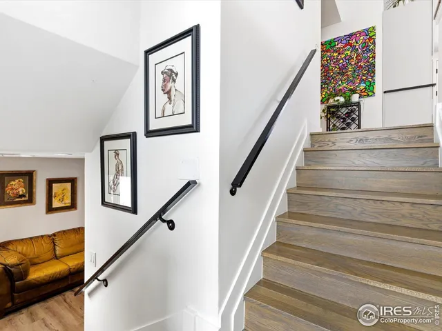 a view of staircase with wooden floor and paintings on the walls