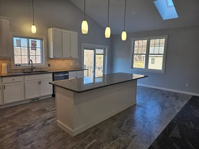 a kitchen with granite countertop a sink a stove cabinets and wooden floor