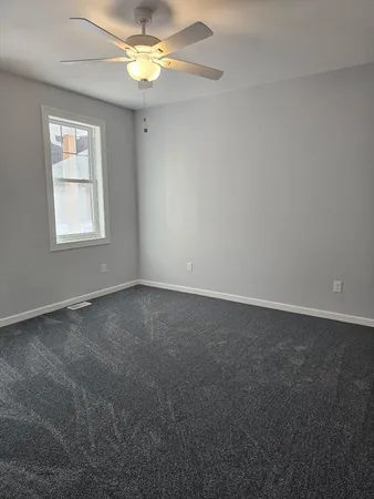 an empty room with a window and a fan