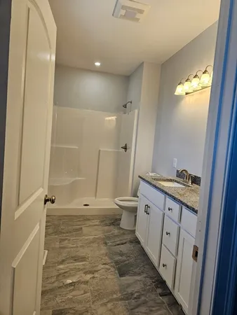 a bathroom with a granite countertop sink toilet and shower