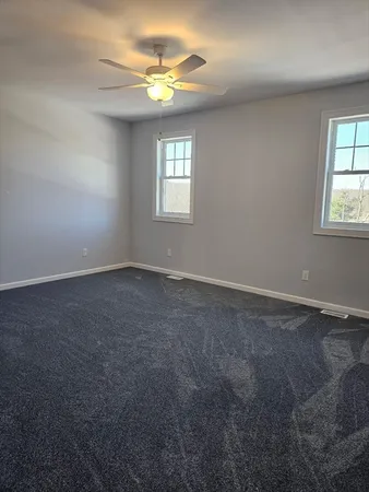 an empty room with windows and chandelier fan