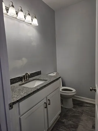 a bathroom with a granite countertop sink a toilet and a mirror