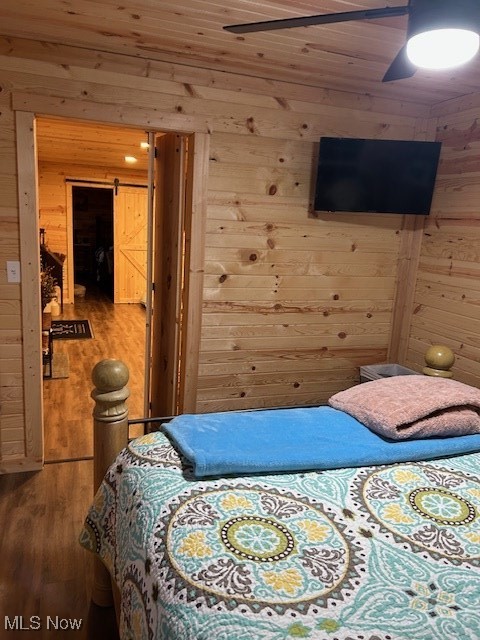 2445 McCord Hill Road Wellsburg, WV 26070 - Photo 8 of 37 Bedroom with a barn door, wood walls, wood ceiling, wood finished floors, and a ceiling fan