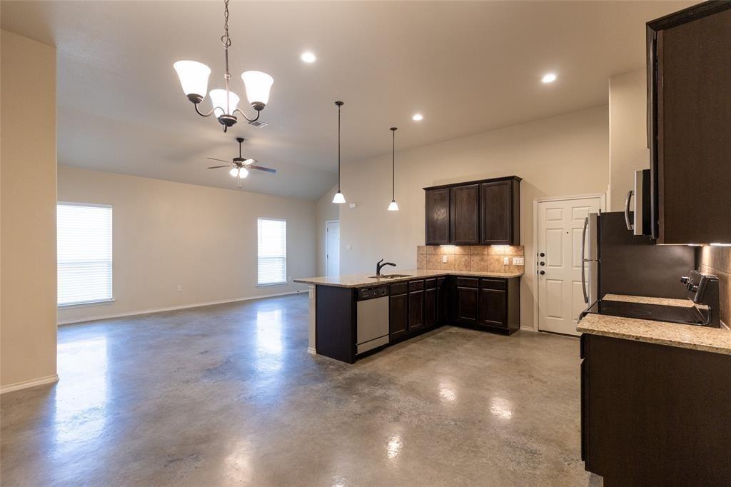 351 Joanne Loop, Unit A Buda, TX 78610 - Photo 8 of 17 An open concept design seamlessly connects the kitchen and living area, featuring polished concrete flooring.