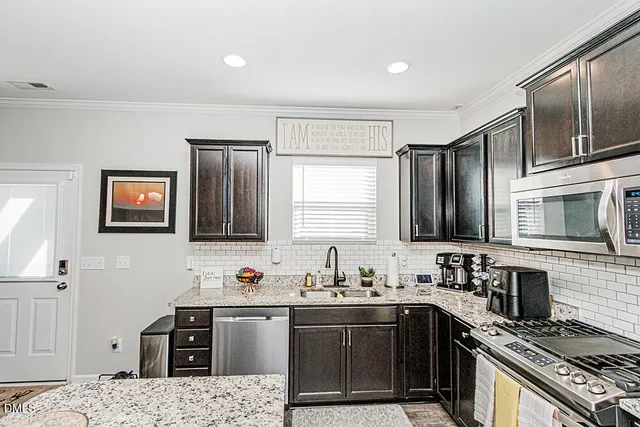 a kitchen with stainless steel appliances granite countertop a sink stove microwave and refrigerator