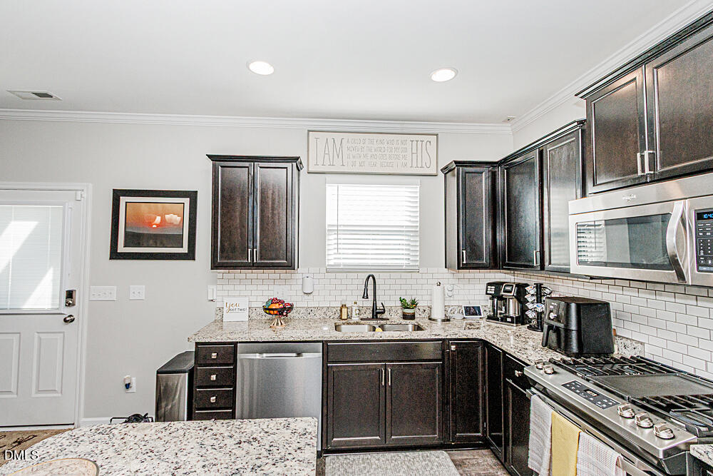 3425 Teravista Way Raleigh, NC 27616 - Photo 17 of 49 a kitchen with stainless steel appliances granite countertop a sink stove microwave and refrigerator