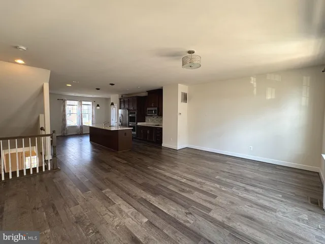 a view of a kitchen and an empty room with wooden floor