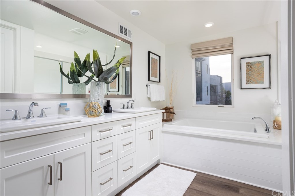 82 Ballast Point Tustin, CA 92782 - Photo 11 of 30 a bathroom with a granite countertop sink a large mirror a bathtub and next to a window