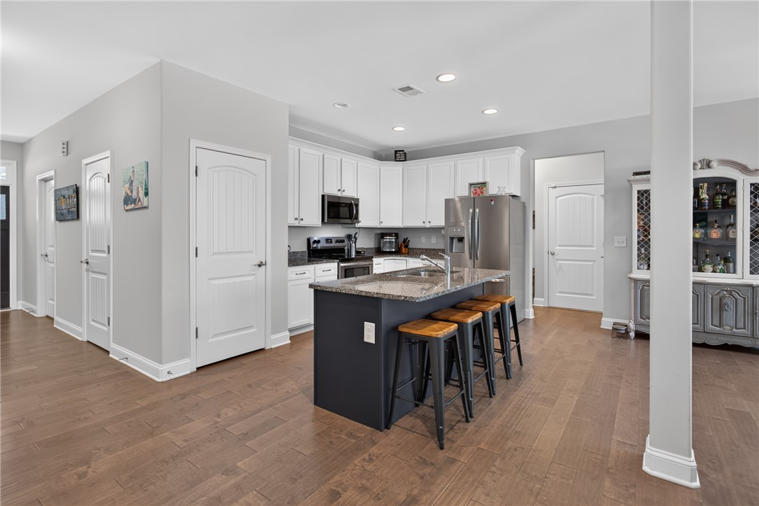 711 Barnes Road Seneca, SC 29672 - Photo 4 of 34 A contemporary kitchen features an inviting island with seating, granite countertops, and hardwood floors.