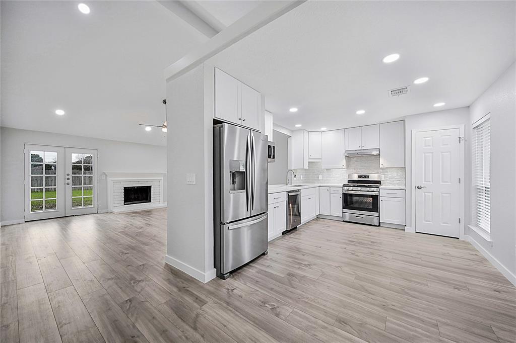 a kitchen with stainless steel appliances a refrigerator and wooden floor