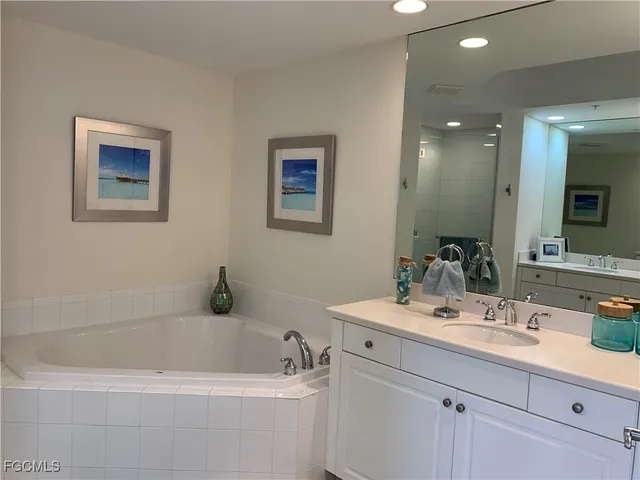 a bathroom with a tub a sink and mirror