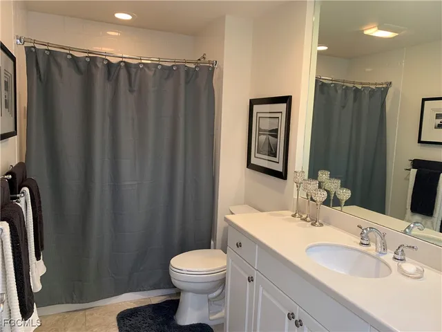 a bathroom with a sink a toilet a mirror and shower curtain