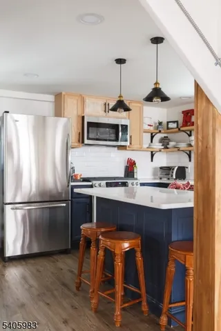 a kitchen with stainless steel appliances granite countertop a refrigerator a stove and a wooden floors