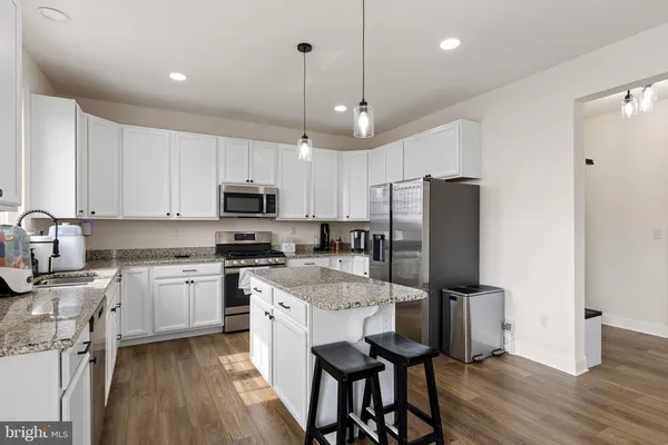 a kitchen with granite countertop a center island stainless steel appliances and wooden floor