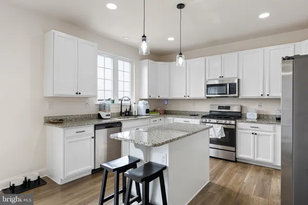 a kitchen with stainless steel appliances granite countertop white cabinets a stove a sink and a refrigerator